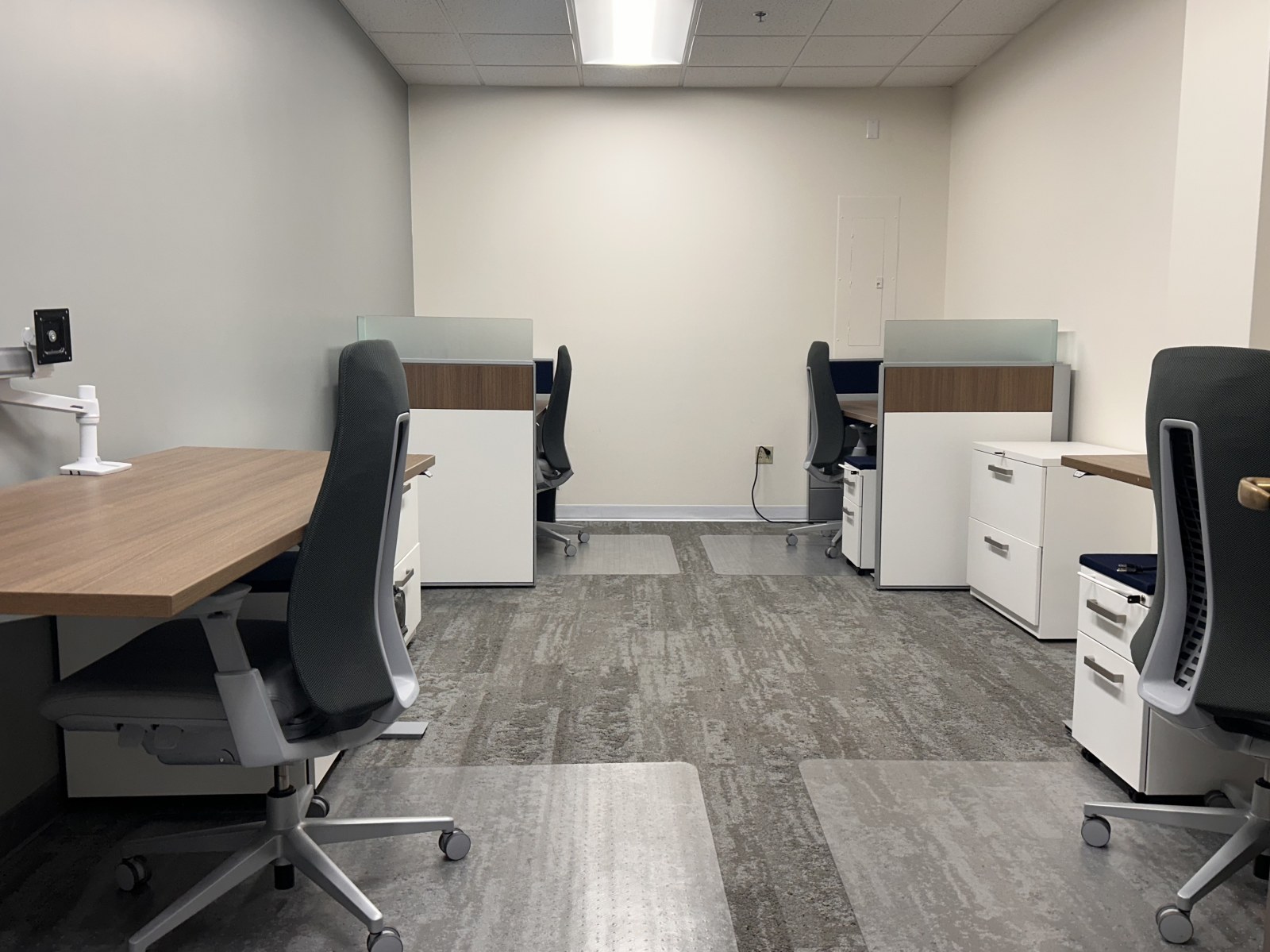The Team Room doorway view with desks, chair mats, and gray carpet
