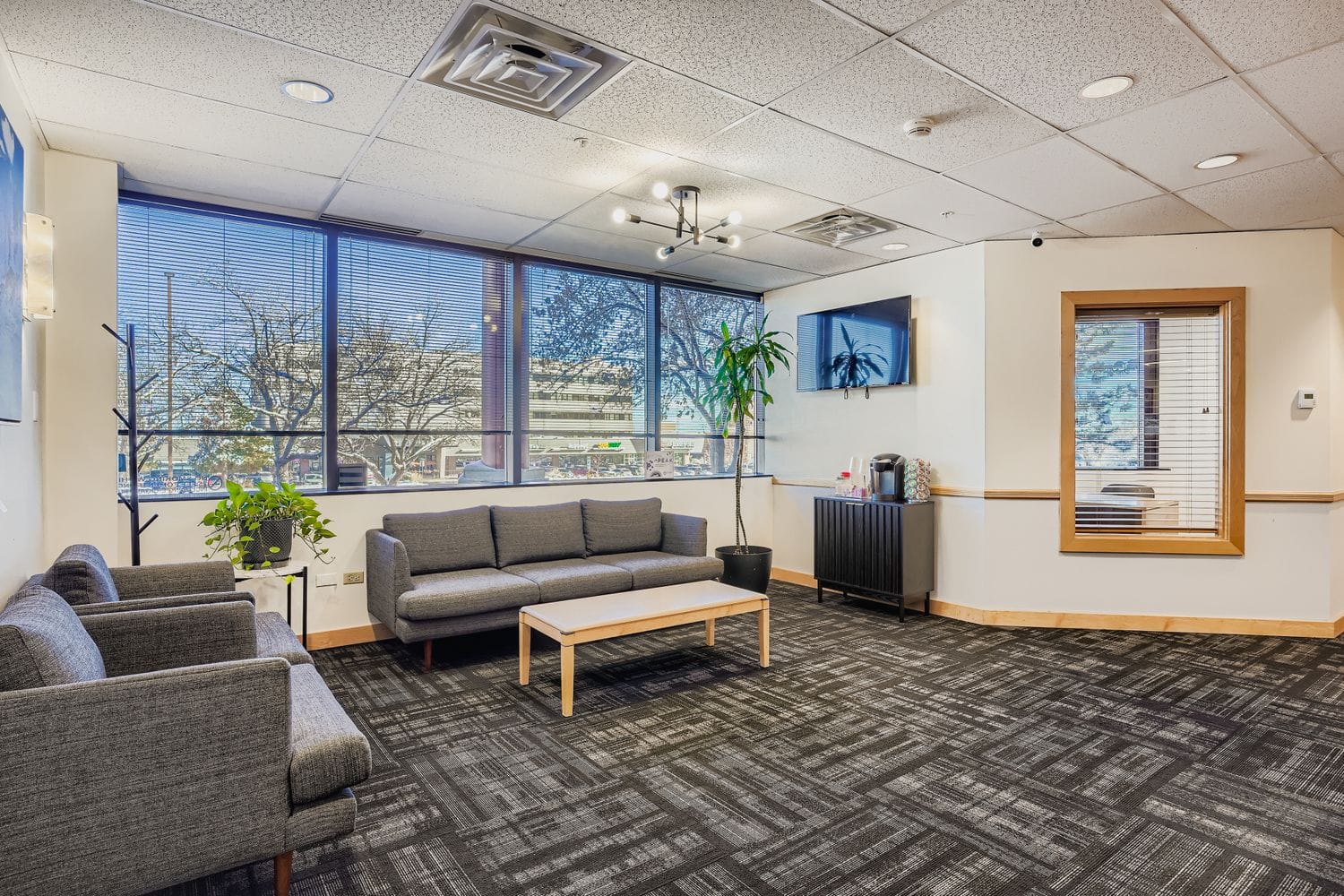 Bright modern office lobby with comfortable seating and large windows showing city view.