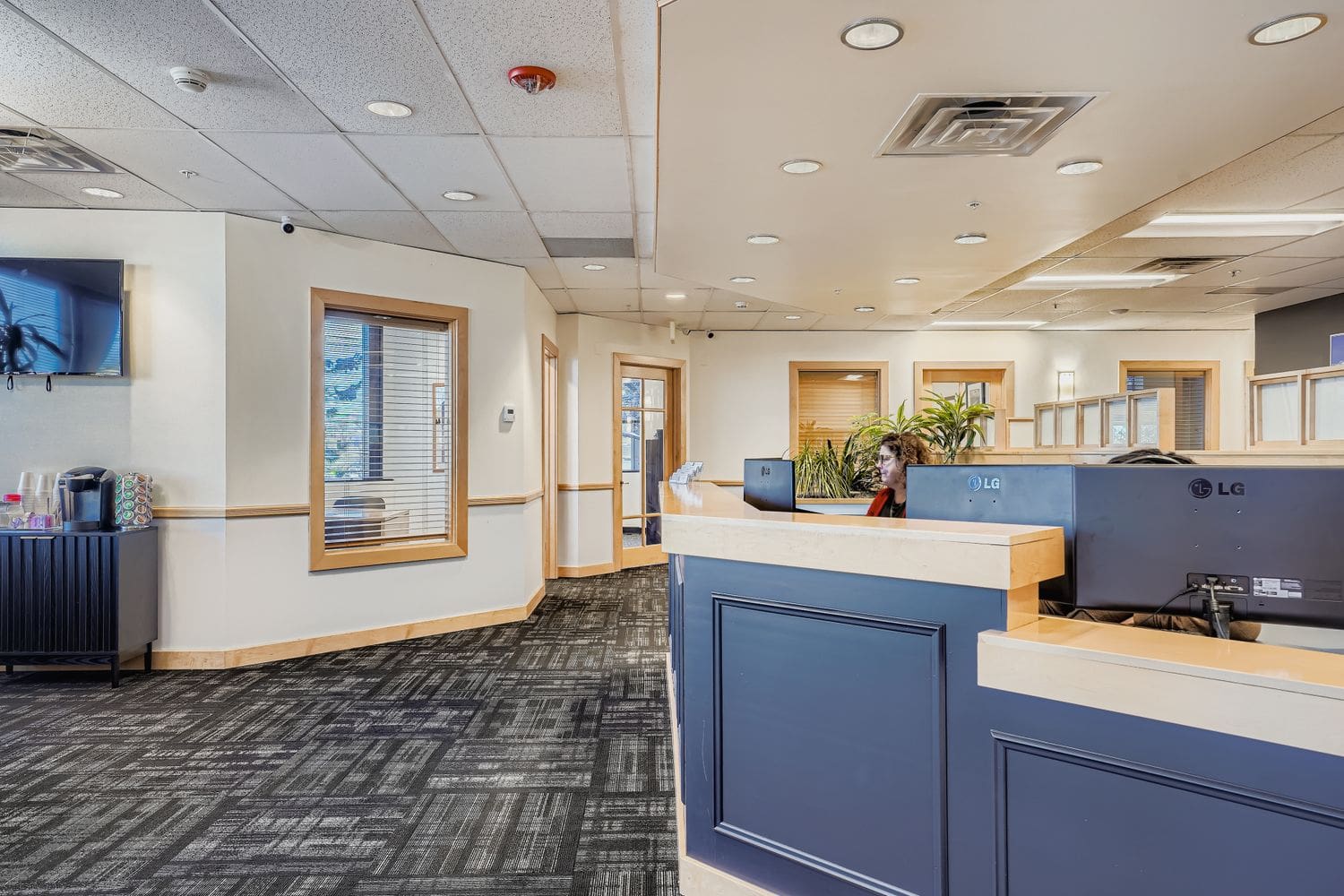 Modern business office reception area with professional front desk and workspaces.