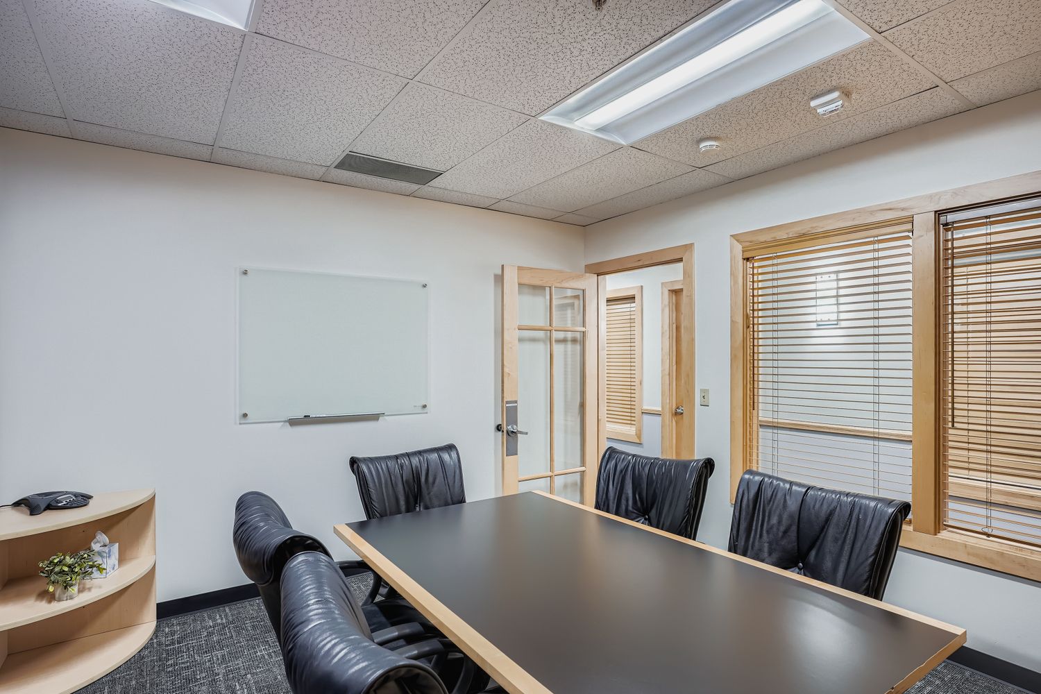 Modern office meeting room with conference table and comfortable black chairs, perfect for business collaboration and workspace solutions.