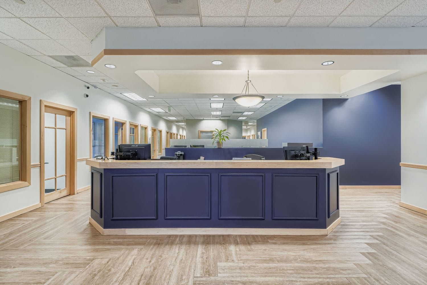 Modern office reception area with blue and beige decor, wooden accents, and natural light.