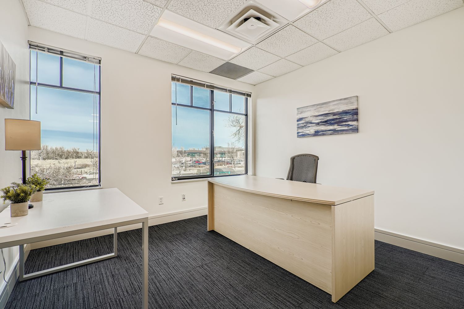 Modern office reception area with large windows, stylish desk, and professional decor for flexible workspace solutions.