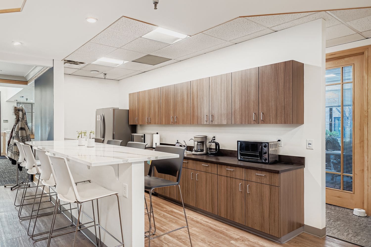 Modern office kitchenette with coffee maker, microwave, and storage cabinets for workspace convenience.
