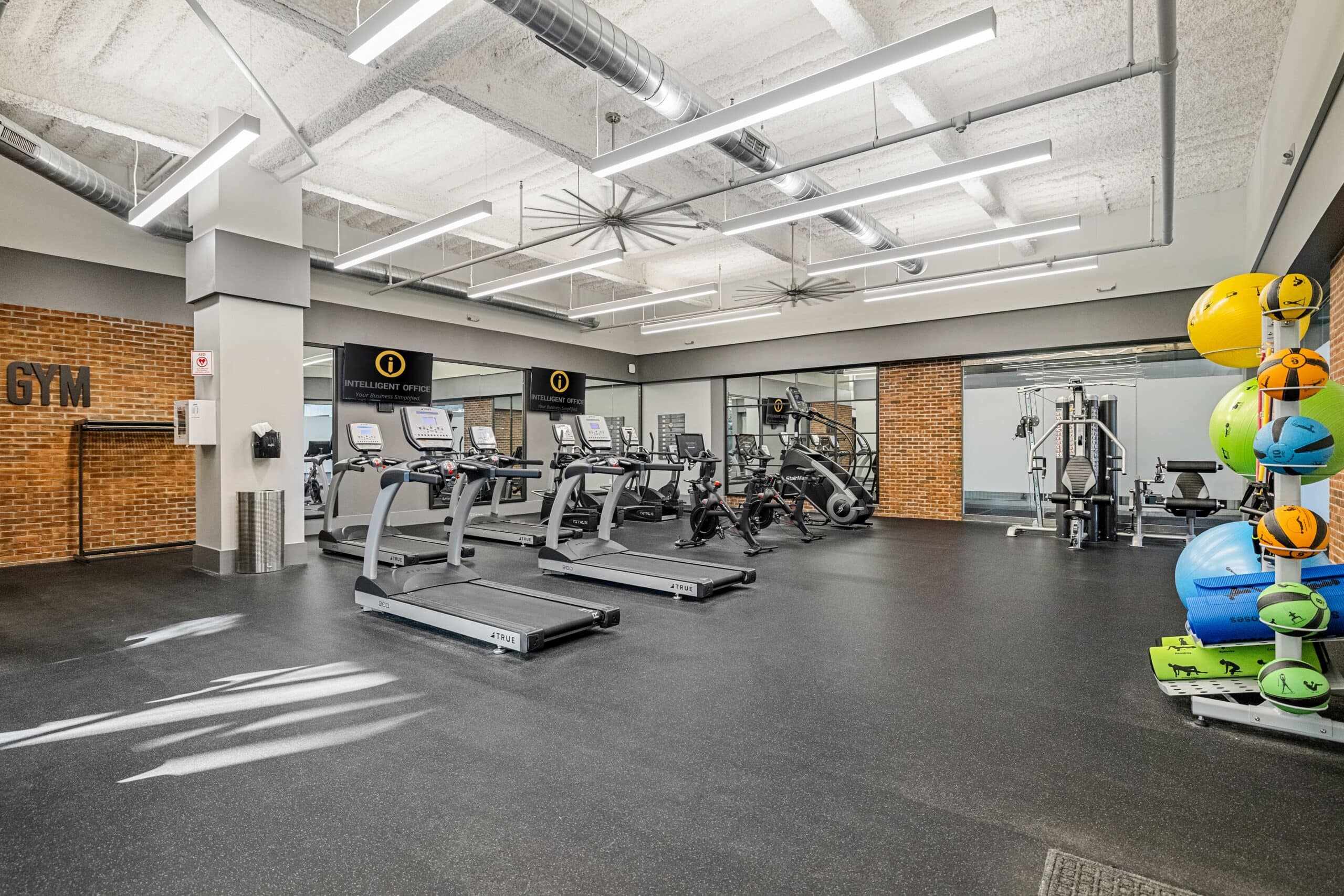 Modern coworking gym space at Intelligent Office Troy with fitness equipment and vibrant exercise ge.