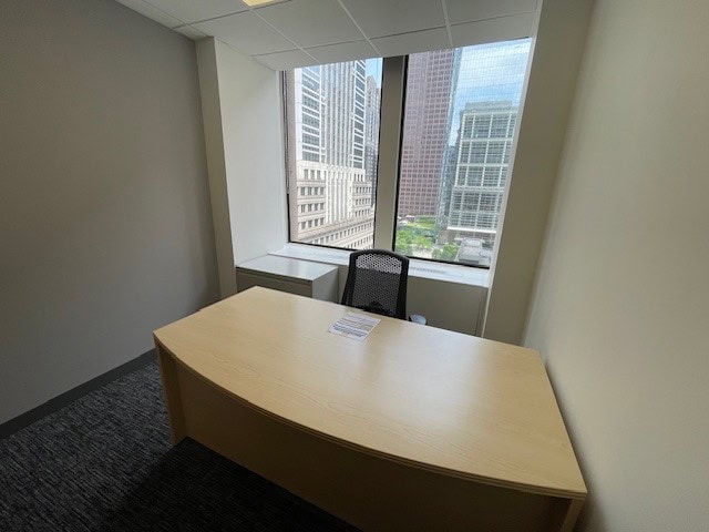 Office workspace with a view of Philadelphia skyscrapers, modern furniture, and large windows.