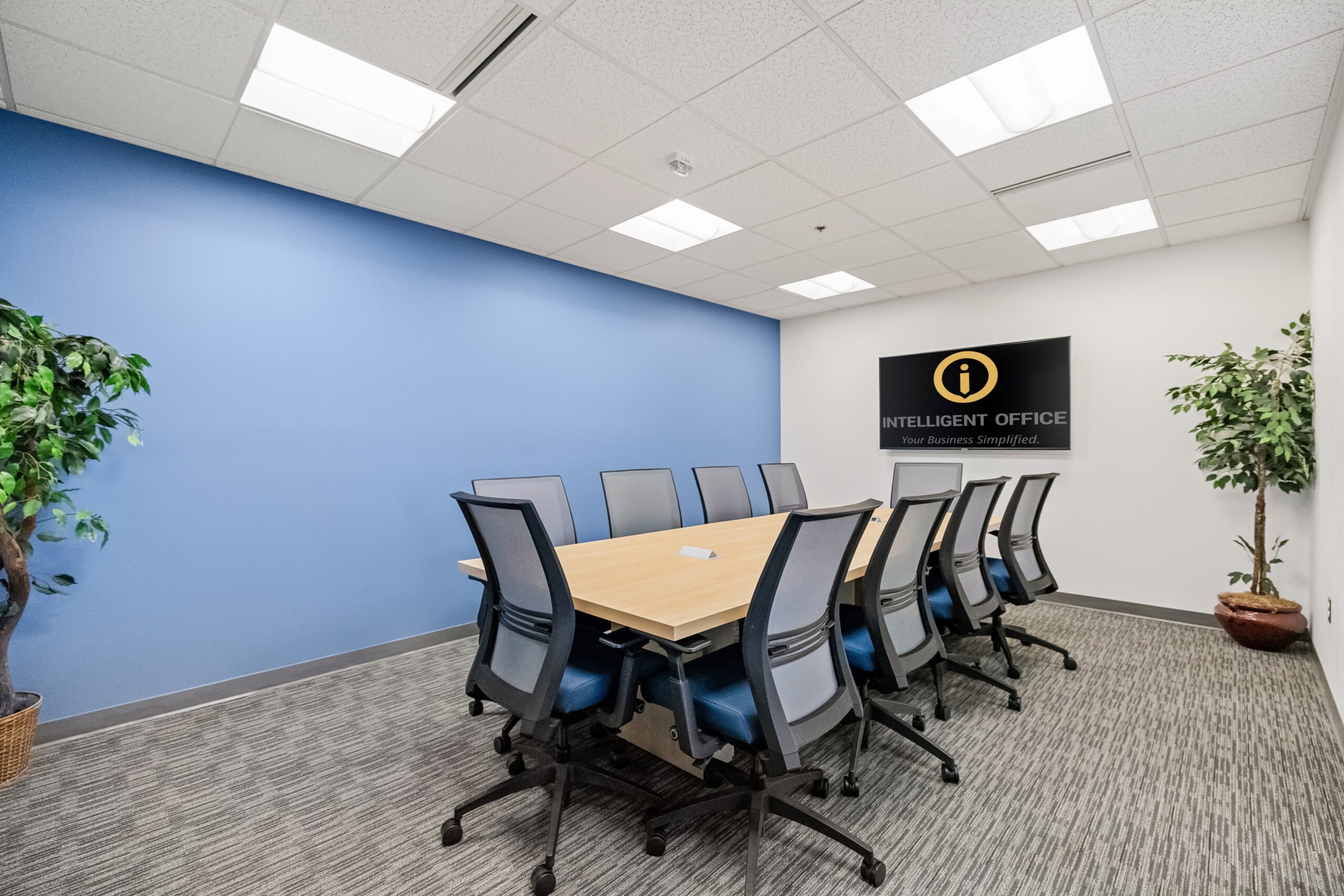 Flexible office meeting room with modern chairs and a large screen displaying Intelligent Office bra.