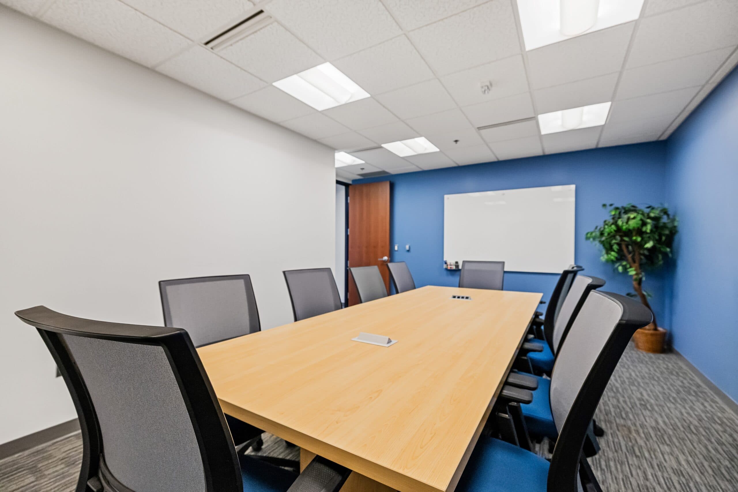Modern conference room with a large wooden table and black chairs, ideal for meetings at Intelligent.