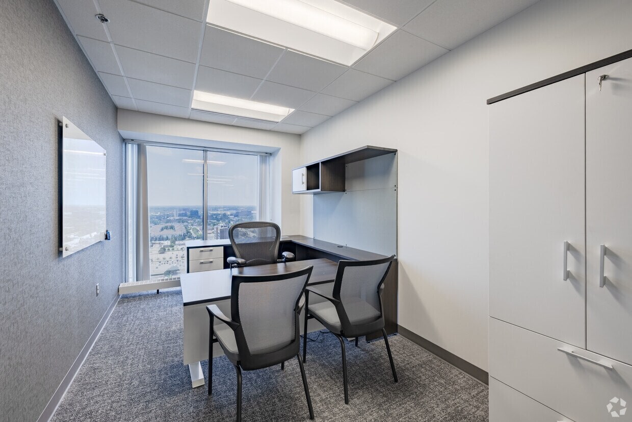 Modern office space with a large window, desk, chairs, and storage, ideal for professional business meetings.