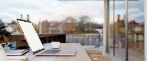 Modern office workspace with a laptop, coffee, and large windows for productive working environment.