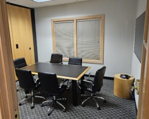 Modern office meeting room with conference table and black leather chairs for professional business meetings, workspace, and corporate environment.
