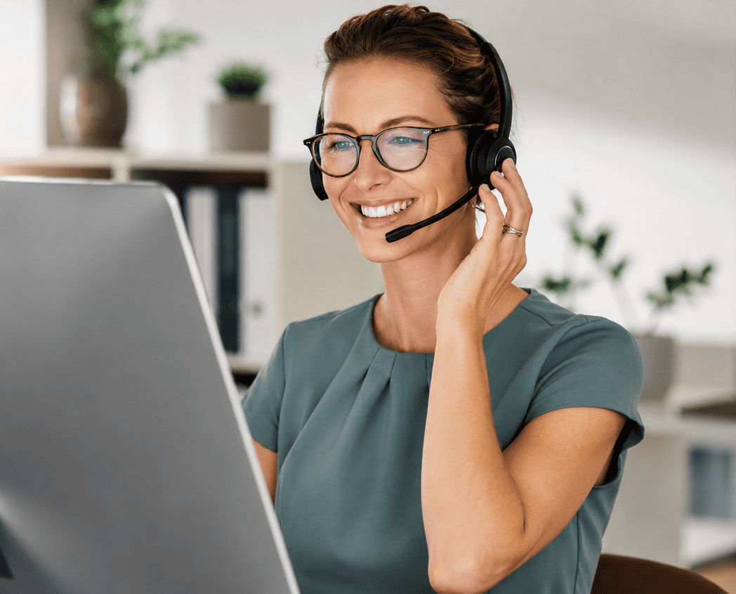 Professional virtual receptionist wearing a headset while assisting clients from a modern office.