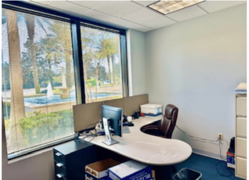 Office workspace with large window and scenic outdoor view.