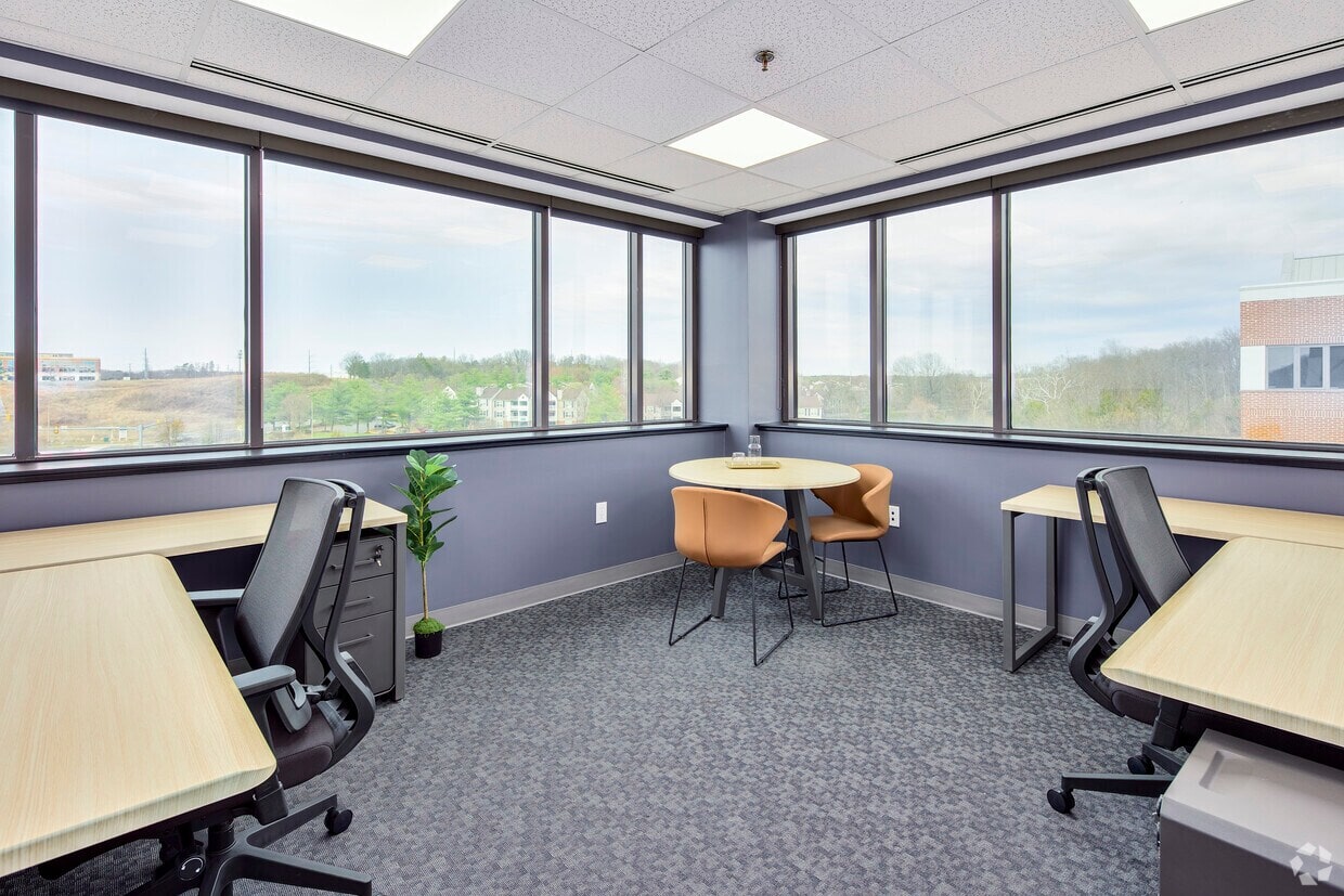 Bright office with large windows and ergonomic desks for productive work environments.