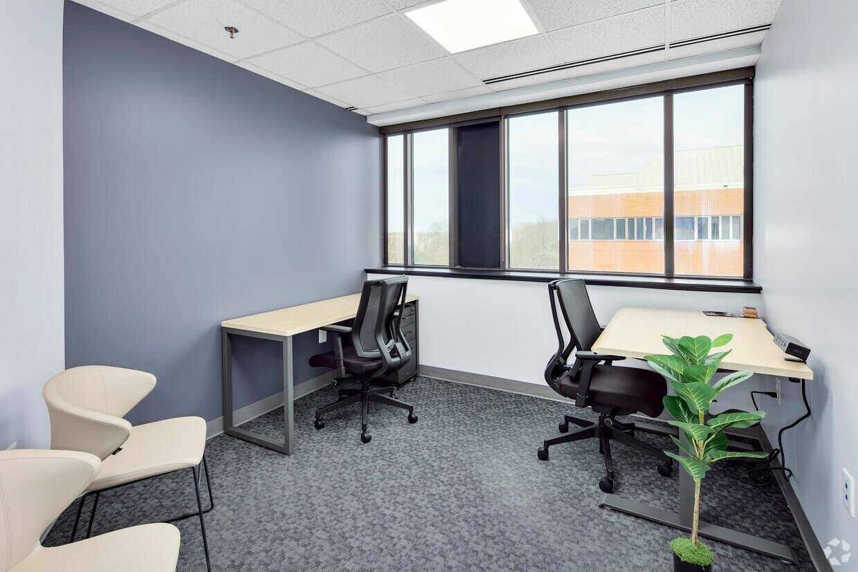 Office workspace with large windows and ergonomic chairs for productivity.