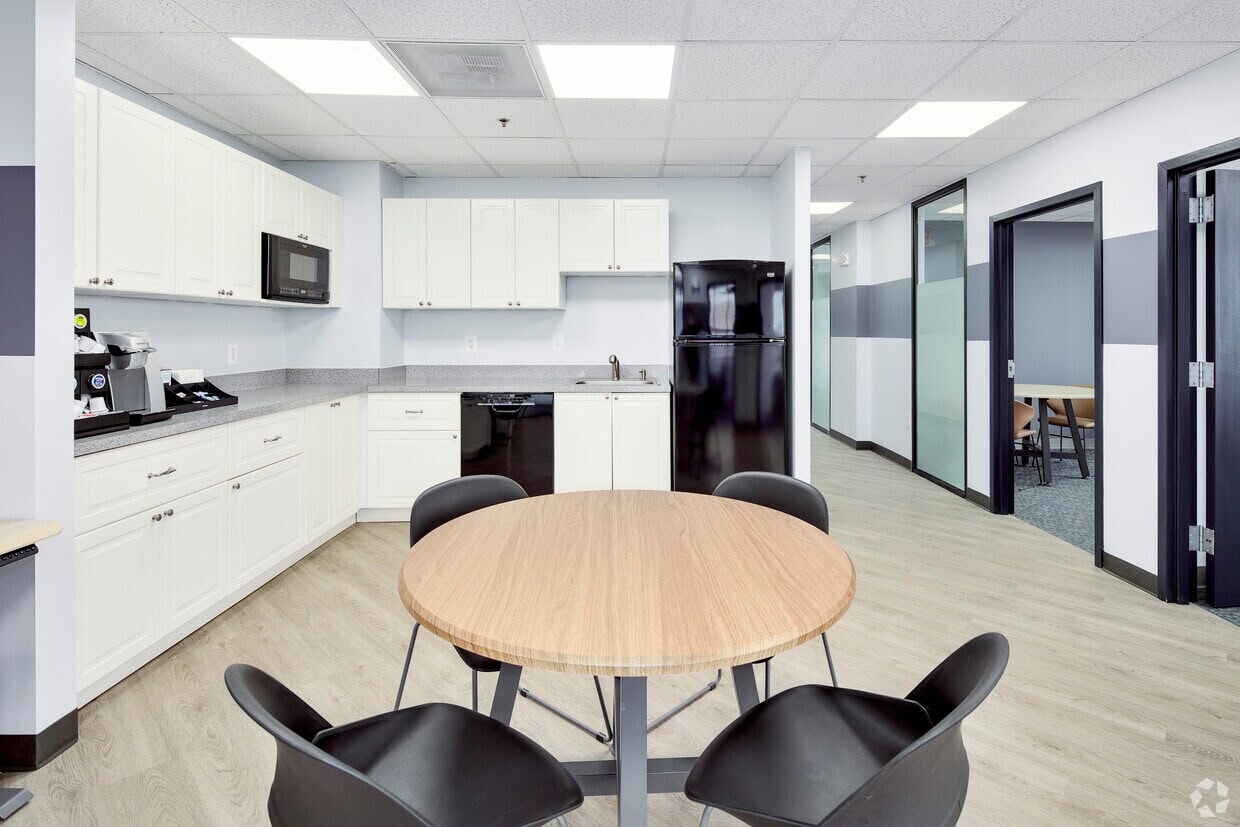 Office kitchenette with white cabinets, microwave, and refrigerator.