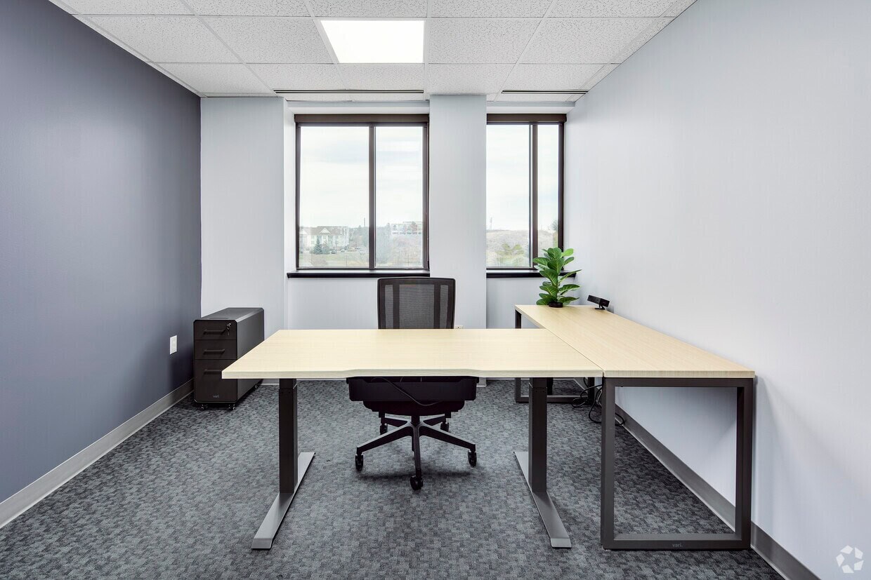 A clean, professional office with a desk, chair, and natural light from large windows.