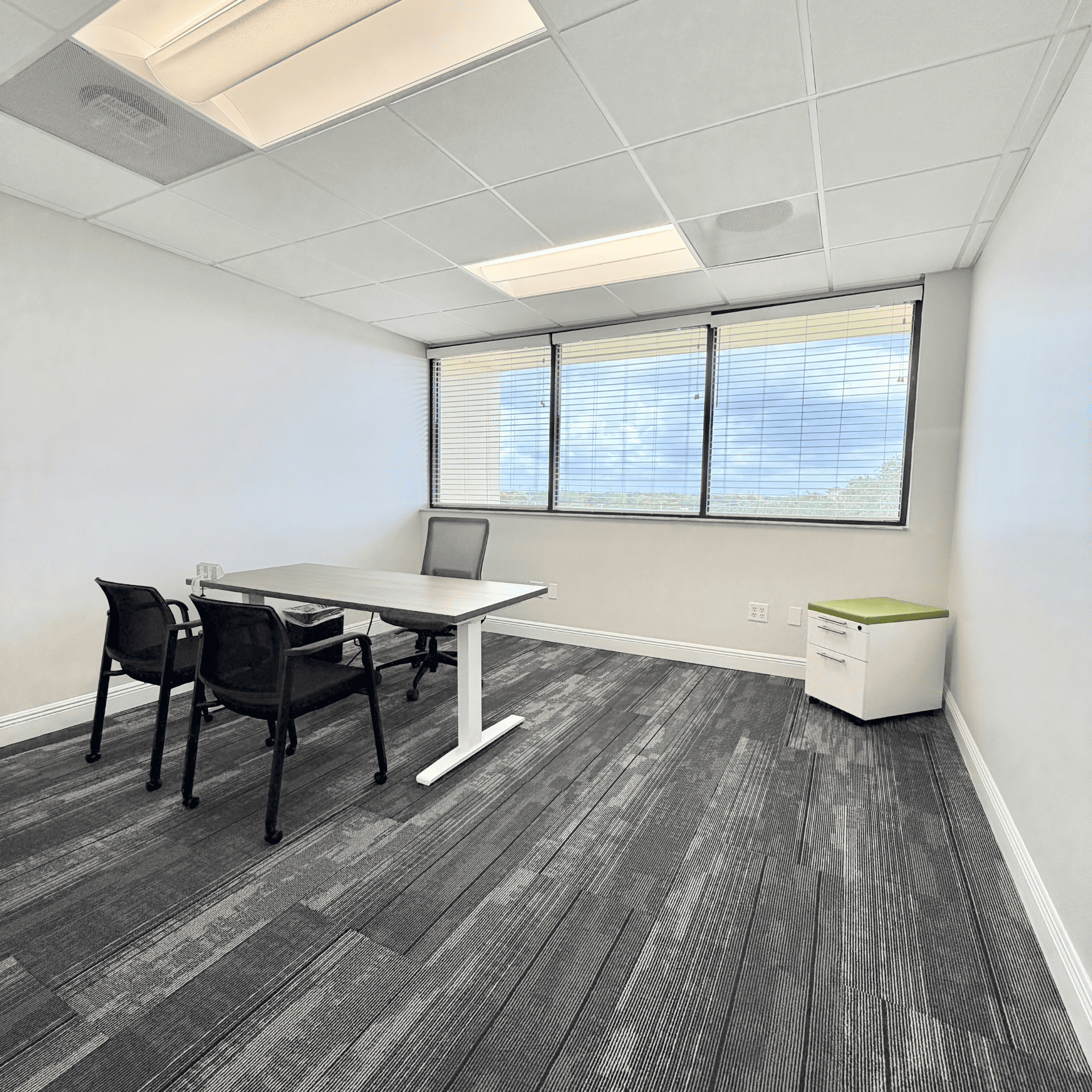 A comfortable, modern office space with large windows, a desk, and chairs, ideal for professional wo.