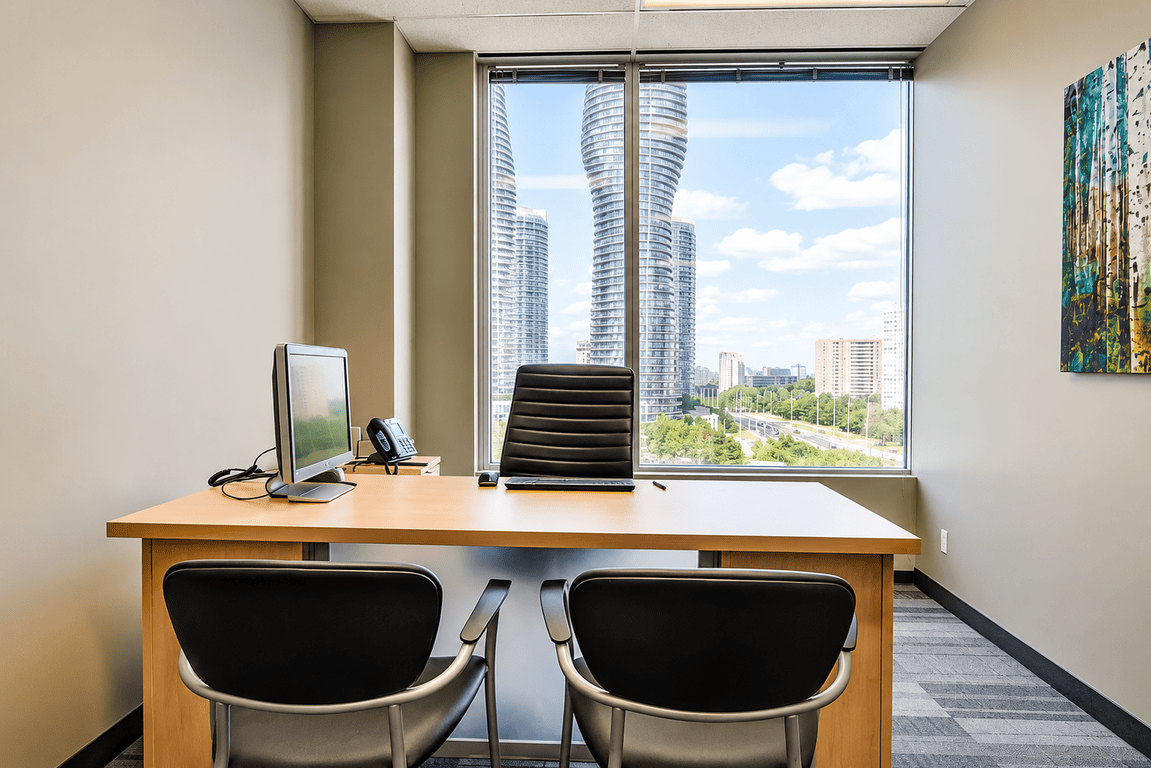 Executive suite with desk seating, large window, and city skyline view.